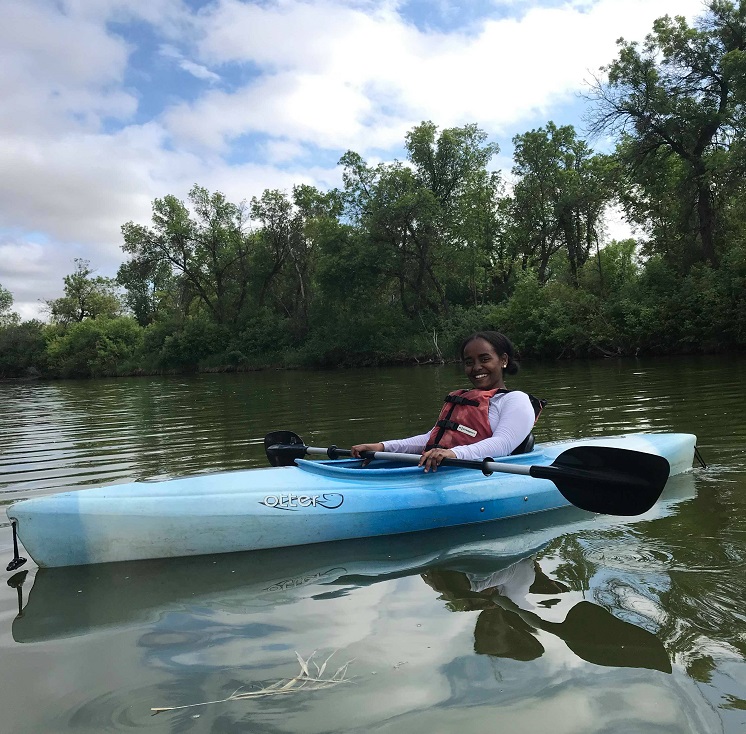 A young woman leaning back and smiling while posing in a kayak. 